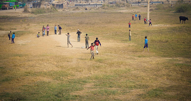 Children playing cricket in an open field
